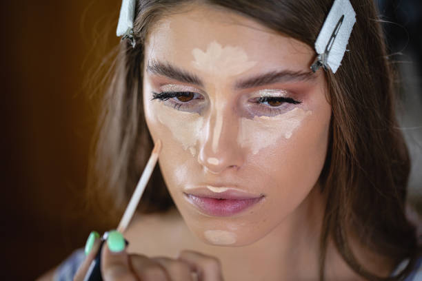 Beautiful model being applied a foundation make-up in a beauty salon stock photo