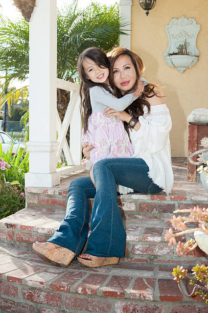 hermosa madre e hija sentado en porche de entrada - flared jeans fotografías e imágenes de stock