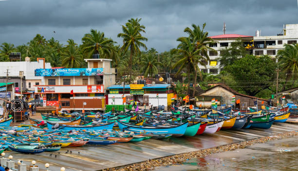 Beautiful photo of coastal beach village on Western ghats of India, where Colorful fishing canoes are anchored off the sea shore during off season and rough weather forecast. Concept of colorful asia, coastal village, southern india, marine economy, rough weather forecast etc. based on the interpretation of the user and creativity. Beautiful photo of colorful canoes parked on the beach of a coastal village of Western Ghats of India. These fishing canoes are anchored at the coast due to off season during rainy season when the weather forecast is of rough seas. Marine economy gets affected due to this. Besides pleasant and serene scene of a typical south Indian coastal village. karnataka stock pictures, royalty-free photos & images