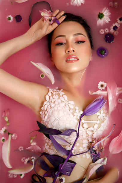 Beautiful portrait of a woman with flowers and petals in rose water. Facial cosmetics that moisturize the skin stock photo