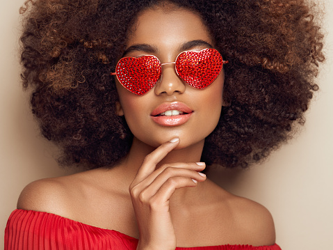 Beautiful portrait of an African girl in sunglasses in the shape of hearts. Valentine's Day. Symbol of love
