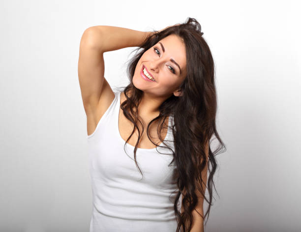 Beautiful positive fun happy woman in white shirt with toothy smile showing her epilation armpit on white background stock photo
