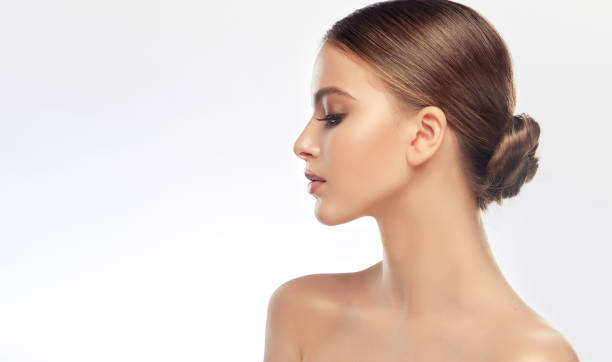 Beautiful profile  of young woman face wearing in elegant makeup in beige colors. Woman grace and beauty. stock photo