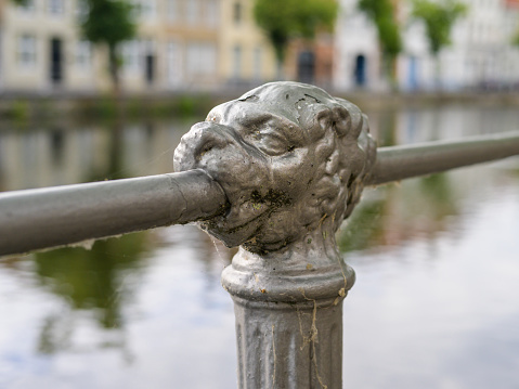 Beautiful railing with head of a lion, canal in Bruges (Belgium), sunny day in summer