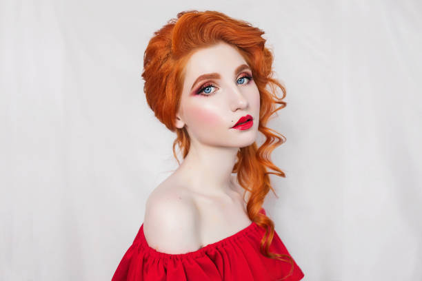Beautiful red-haired girl in red dress posing on white background. Portrait of a woman with red hair  victorian gown stock pictures, royalty-free photos & images