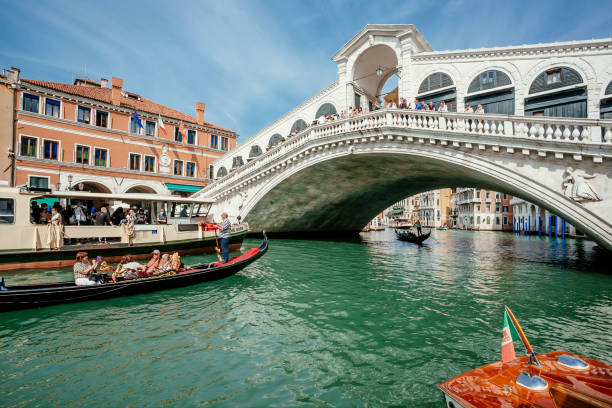 Beautiful Rialto bridge across canal with gondolas and riverboats of famous city stock photo