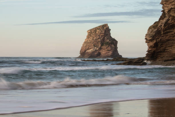 beautiful rock cliff deux jumeaux in sunset sky on sandy beach of hendaye, basque country, france stock photo