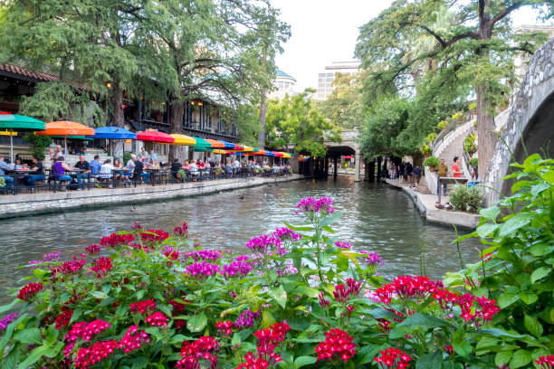 Beautiful San Antonio Riverwalk in Early Fall This view shows some of the scenery along the famous San Antonio Riverwalk in the heart of the Texas city.  This picture was taken in the early fall while the temperatures were still very hot.  Bright umbrellas lining one side of the riverbank can be seen in this shot. has san hawkins stock pictures, royalty-free photos & images