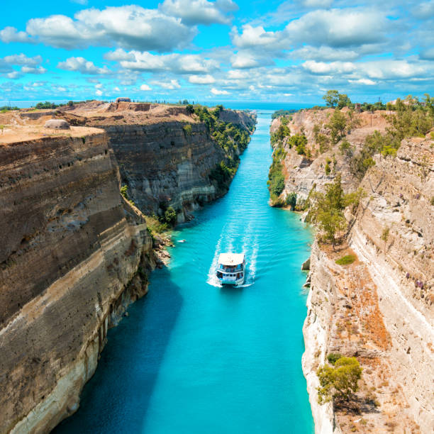 Beautiful scenery of the Corinth Canal Beautiful scenery of the Corinth Canal in a bright sunny day against a blue sky with white clouds. Among the rocks floating white ship in turquoise water. peloponnese stock pictures, royalty-free photos & images