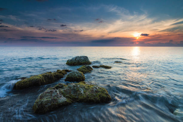 Beautiful seascape with rocks leading out to the sunset stock photo