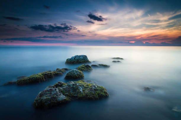 Beautiful seascape with stones leading out to the sunset taken with a long exposure stock photo