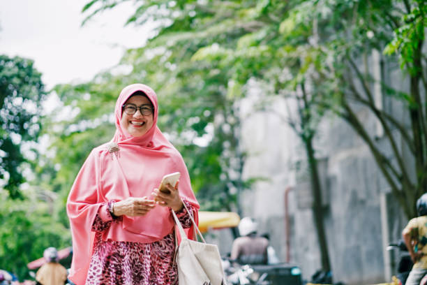 Beautiful Senior Islam Woman with Mobile Phone Ramadan Shopping indonesian woman stock pictures, royalty-free photos & images