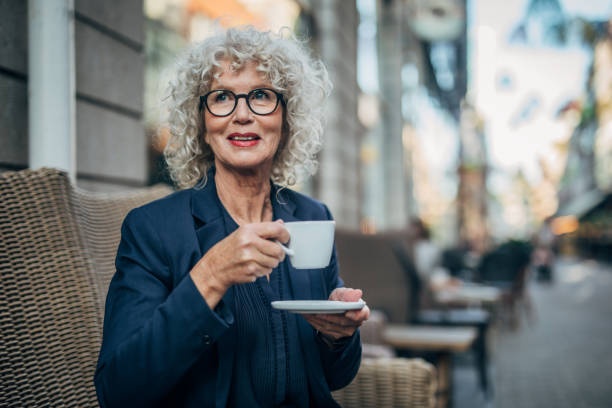 Beautiful senior woman drinking a hot drink Beautiful senior woman drinking a hot drink in coffee shop curley cup stock pictures, royalty-free photos & images