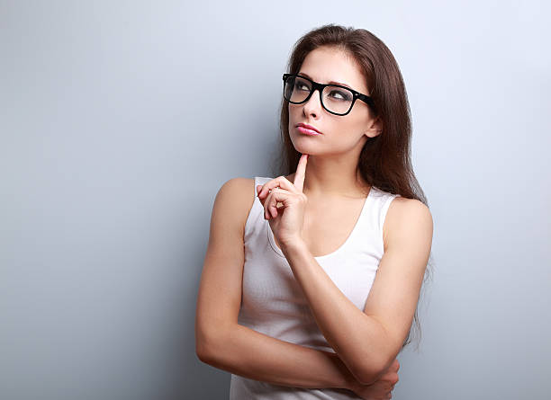 Beautiful serious thinking young woman looking up on empty copy stock photo