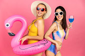 ビキニとピンクの背景に立って笑顔で美しいセクシーなアジアの女性が孤立しています.夏の職業幸せな旅行のコンセプト。