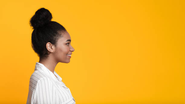 Beautiful smiling african american girl profile portrait over yellow background Beautiful smiling african american girl profile portrait. Black woman looking aside at copy space over yellow background, panorama side view photos stock pictures, royalty-free photos & images