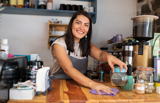 Bella barista sonriente sirviendo café y galletas en cafetería