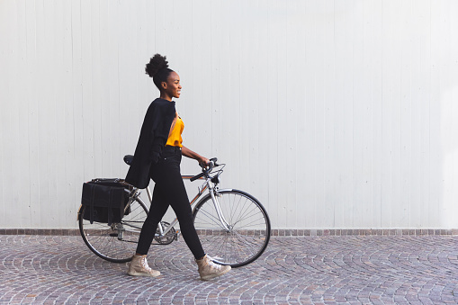 Smiling young woman in business out of the office with her bicycle going home.