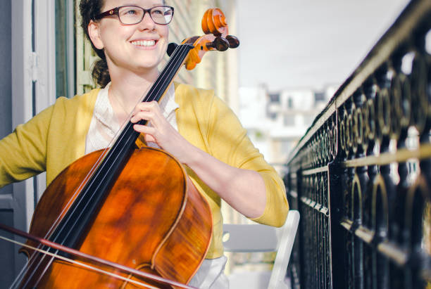 Beautiful smiling young female cellist on a balcony stock photo