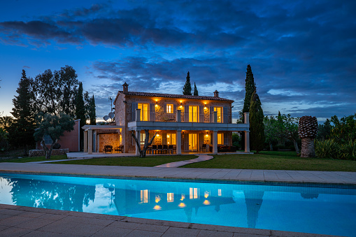 typical spanish finca, house with huge garden and swimming pool with reflections on island of Majorca on cloudy evening
