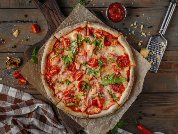 mooie kruidige pizza op een rustieke houten lijst met vlees, tomaten en rucola, gekookt in de oven, hoogste mening - pizza stockfoto's en -beelden
