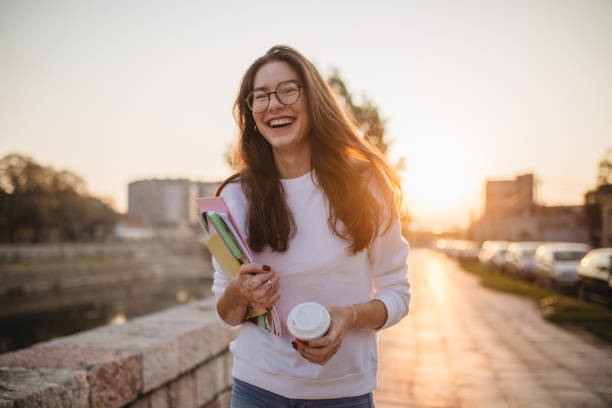 Beautiful student girl with eyeglasses going home from school Young student with notepads and a coffee walking outdoors in sunset. 18 19 years stock pictures, royalty-free photos & images