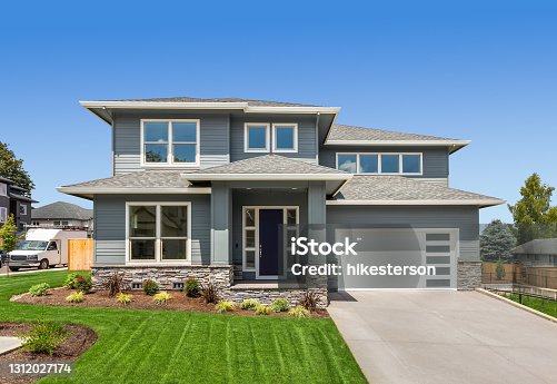 istock Beautiful suburban home exterior on bright sunny day with green grass and blue sky 1312027174