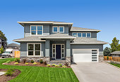 istock Beautiful suburban home exterior on bright sunny day with green grass and blue sky 1312027174