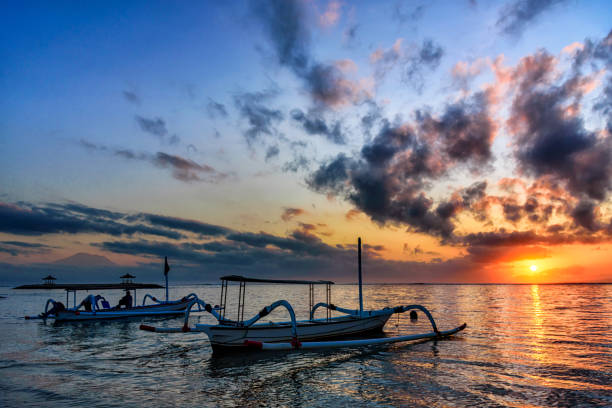 Beautiful sunrise scenery with Jukung is traditional balinese fishing boats at Karang Beach, Sanur, Bali, Indonesia. stock photo