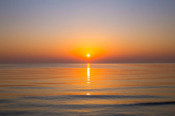 Beautiful sunrise with sea wave against beach on yellow sea stock photo