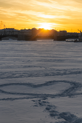 Beautiful sunset and silhouette of a heart on a snowy river in the city of vertical orientation (Saint Petersburg, Russia)