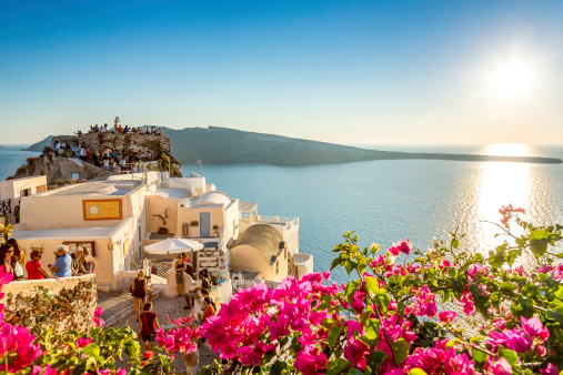Oia, Greece - September 28, 2013:  In Oia Greece every night people come to admire the beautiful sunset which is reflected in the Aegean Sea. People looking for the best place to admire and also to photograph this unique spectacle.  As we can see from this photo, the flowers, the sea, the buildings form a typical and unique landscape to this beautiful island which attracts many tourists annually.