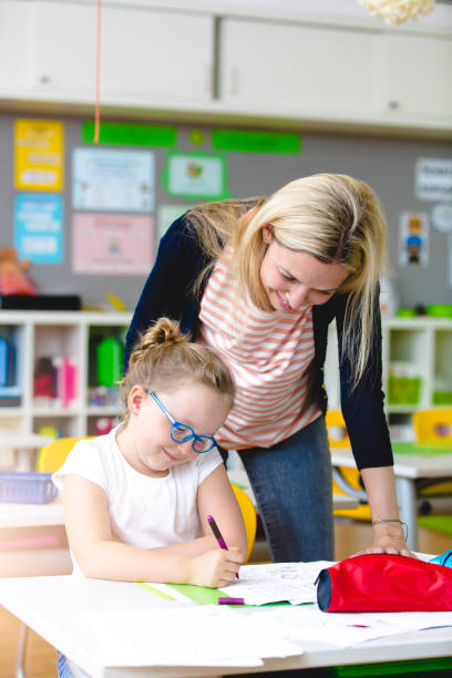 beautiful teacher helps her student to learn stock photo