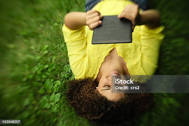 Beautiful teen girl smiling with tablet outside on grass