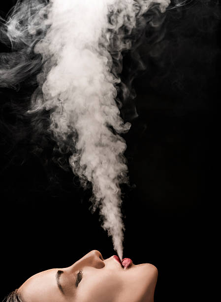 Beautiful woman blowing vape smoke stock photo