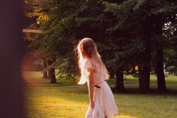 Beautiful woman dancing at sunset A beautiful girl with gorgeous long hair in an elegant white dress dances in the rays of the park. She is outside the city, in nature girls in very short dresses stock pictures, royalty-free photos & images