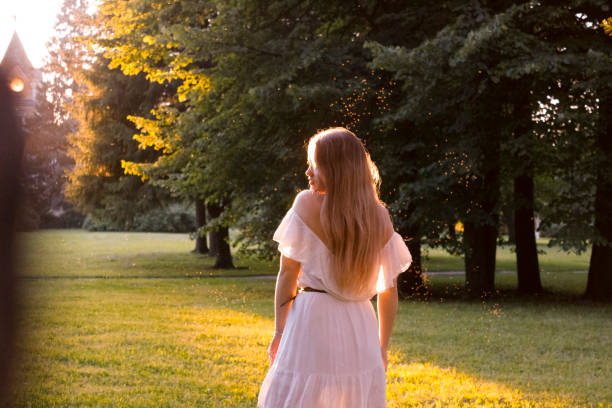 Beautiful woman dancing at sunset A beautiful girl with gorgeous long hair in an elegant white dress dances in the rays of the park. She is outside the city, in nature girls in very short dresses stock pictures, royalty-free photos & images