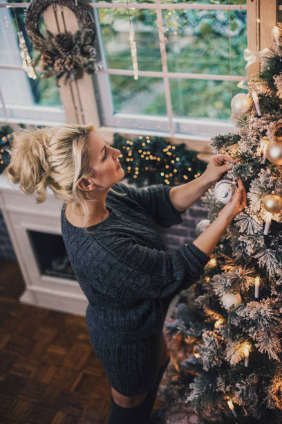 Beautiful woman decorating the Christmas tree at home stock photo