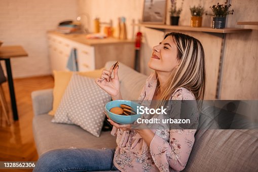 istock Beautiful woman eating cookies at home 1328562306