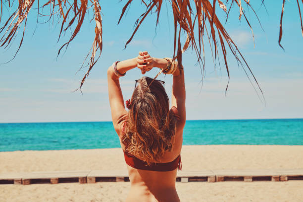 Beautiful woman enjoying on the tropical beach under palm tree. stock photo