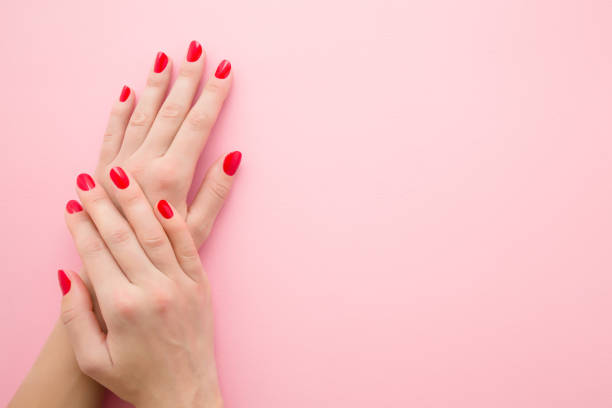 Beautiful woman hands with red nails on light pink table background. Pastel color. Manicure beauty salon concept. Empty place for text or logo. Closeup. Top down view. Beautiful woman hands with red nails on light pink table background. Pastel color. Manicure beauty salon concept. Empty place for text or logo. Closeup. Top down view. beautiful polish girls stock pictures, royalty-free photos & images