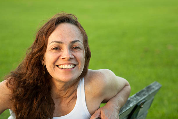 Beautiful woman in the park Beautiful woman smiling and looking straight to camera at park 40 49 years photos stock pictures, royalty-free photos & images