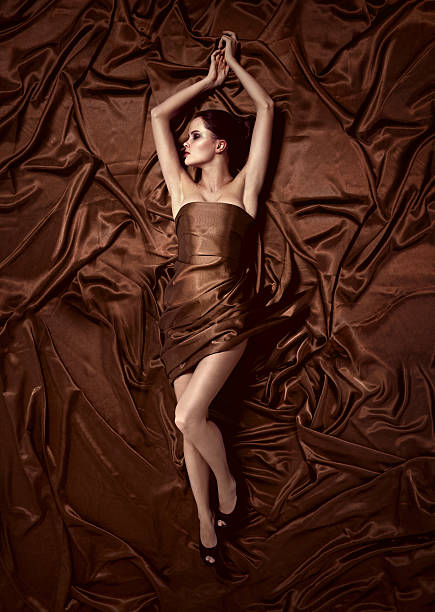 Beautiful woman lying on a chocolate fabric. stock photo