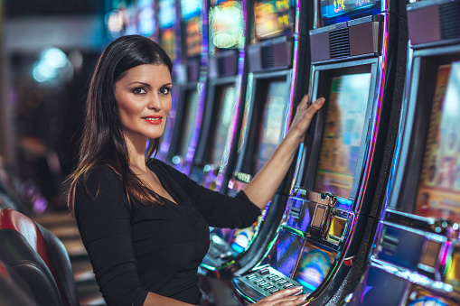 Caucasian Woman Playing Slot Machine In Casino High-Res 
