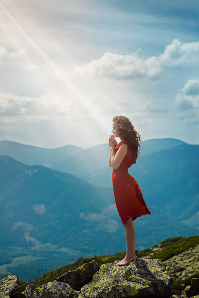 Beautiful woman praying in mountain landscape stock photo
