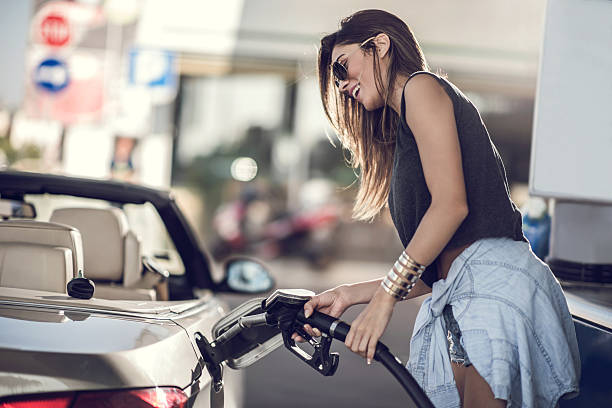 beautiful woman refueling the gas tank at fuel pump. - tanken stockfoto's en -beelden
