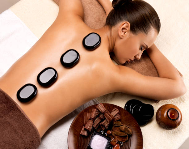 Beautiful woman relaxing in spa salon with hot stones on body. stock photo