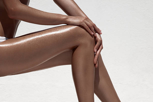 Beautiful woman tan legs. Against white wall. stock photo
