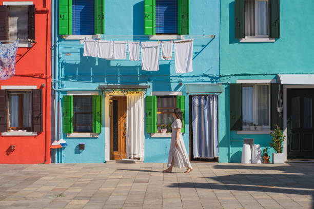 bella donna che cammina davanti alle case di colore. venezia, italia - burano foto e immagini stock
