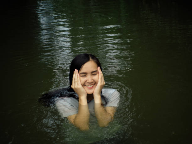 Beautiful woman wearing a white blouse A smiling face happily playing in the stream having fun on holiday. stock photo